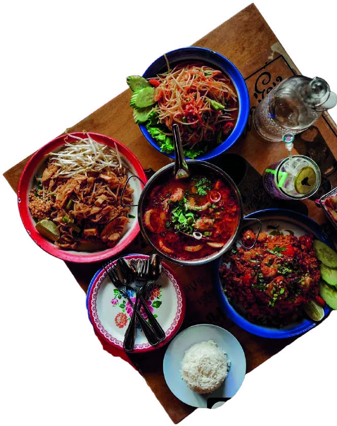 A spread of SiLom dishes on a wooden table